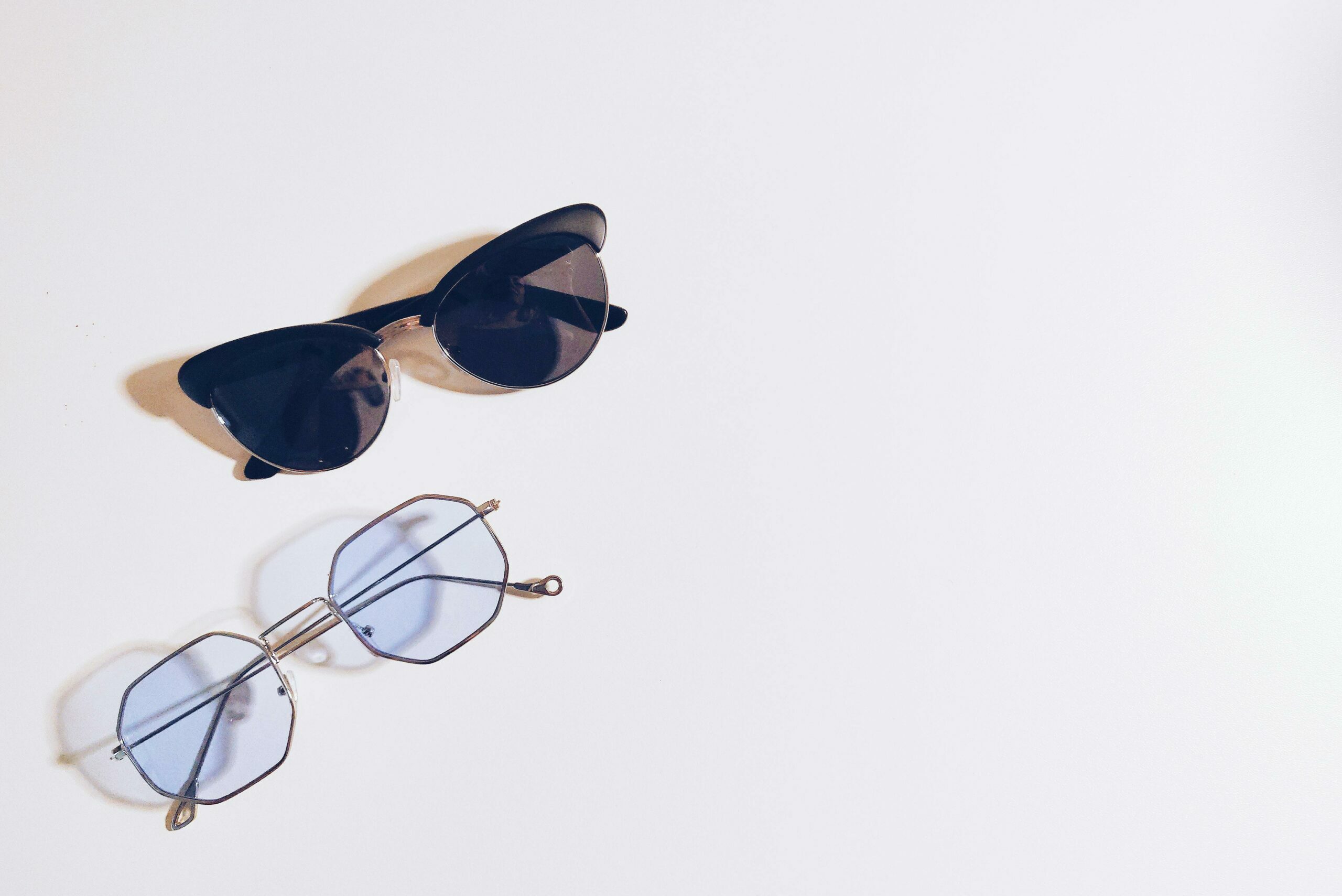 Flat lay of sunglasses and eyeglasses on a white background, perfect for fashion design concepts.